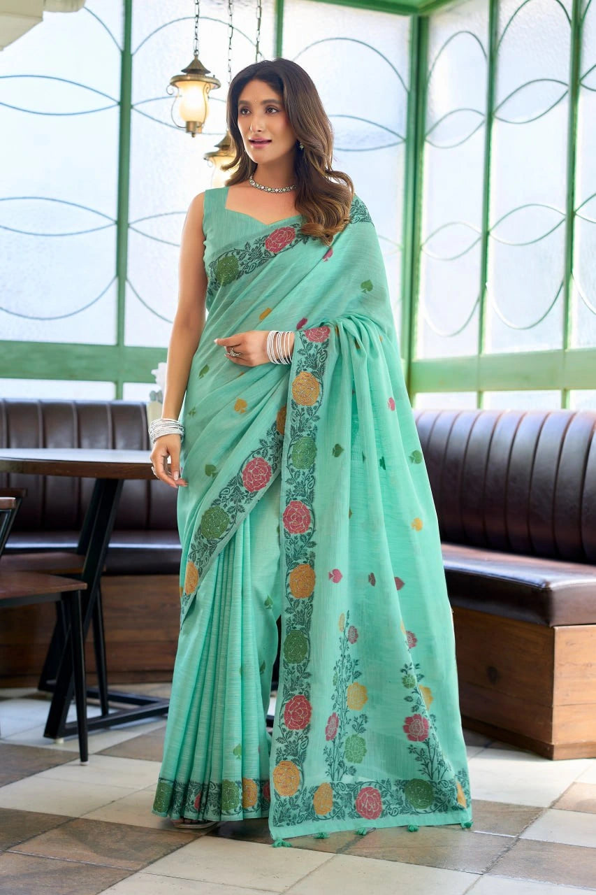 Woman wearing a light green saree with floral patterns indoors.