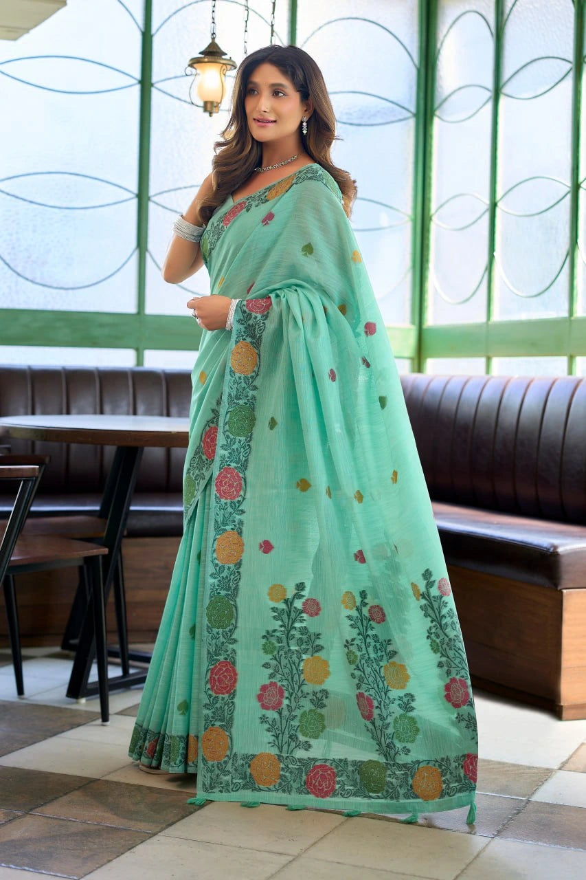 Woman wearing a light green saree with floral patterns in an indoor setting.