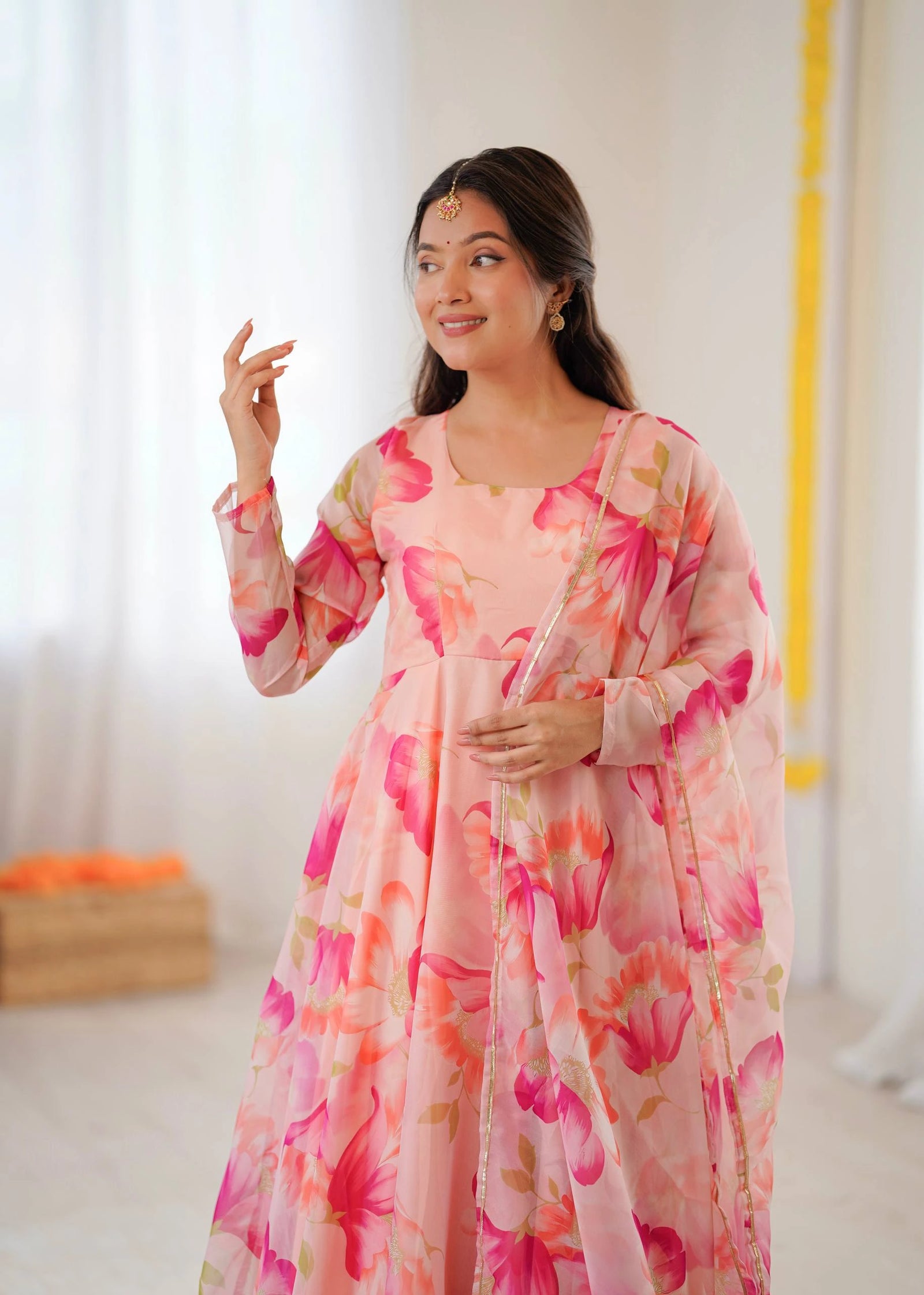 Woman wearing a pink floral dress in a bright room