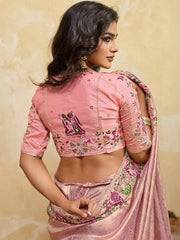Woman wearing a pink embroidered saree with a beige background