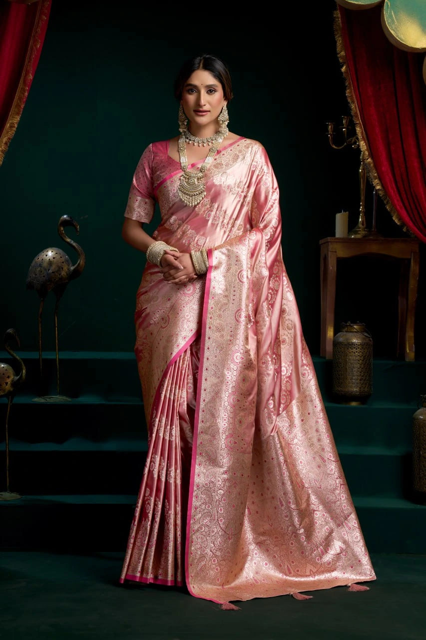 Woman in a pink saree standing in a decorative setting with red curtains and green walls.