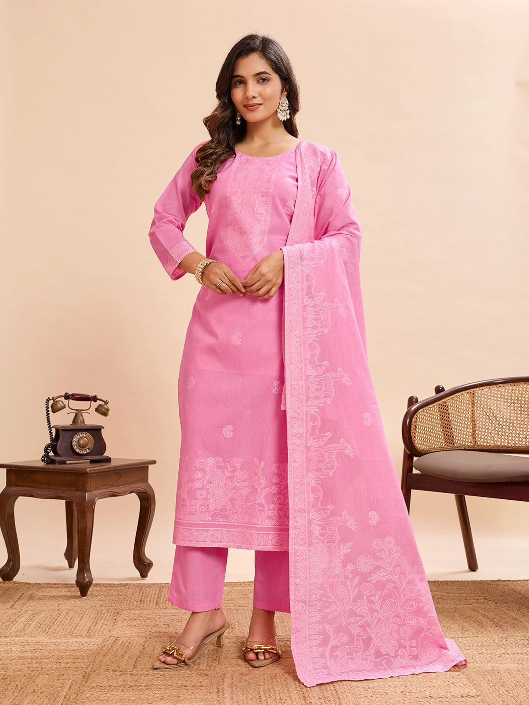 Woman wearing a pink traditional outfit with a matching dupatta in a room setting.