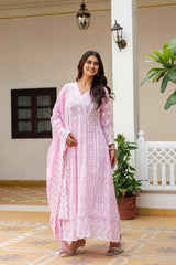 Woman in a pink traditional outfit standing in a decorative indoor setting.