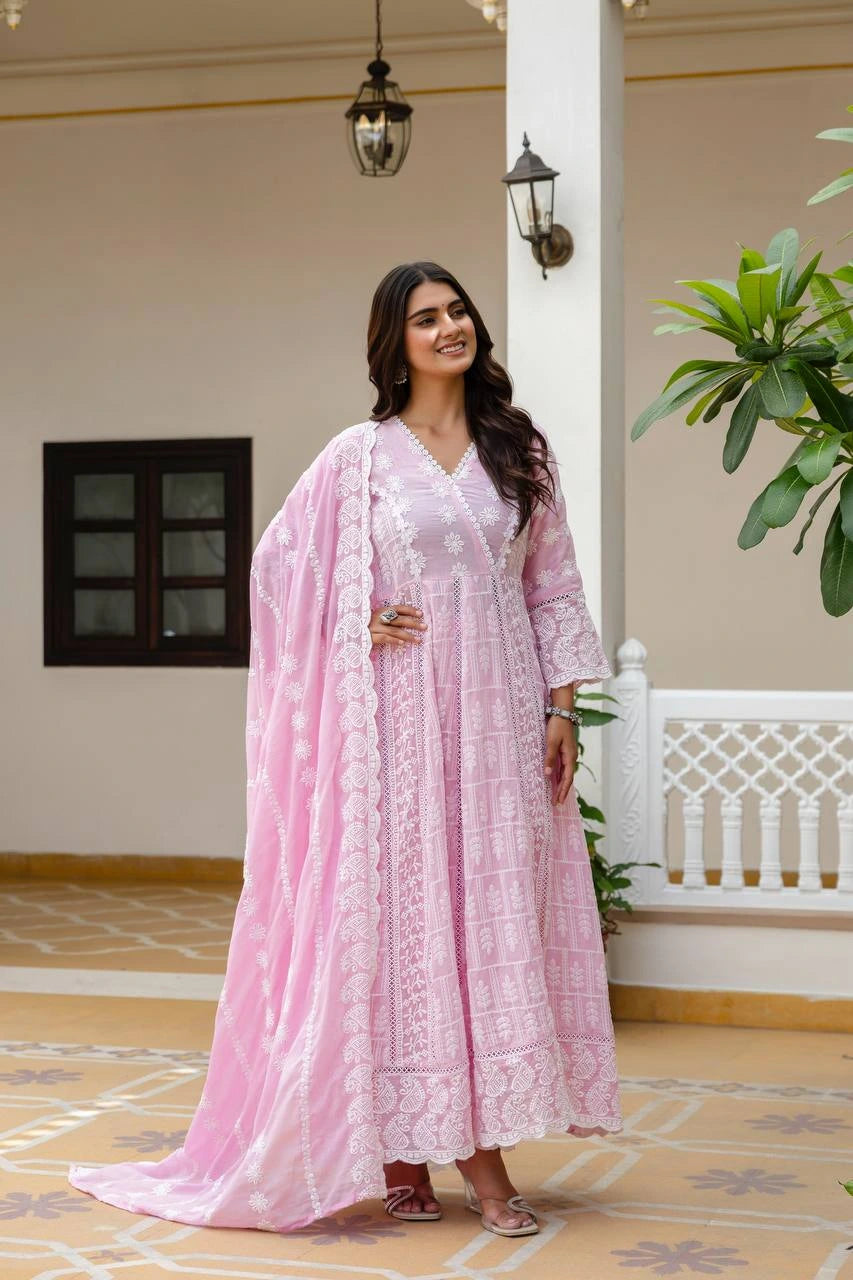 Woman in a pink traditional outfit standing in an indoor setting with decorative elements.