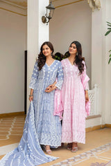 Two women in traditional outfits standing in a decorative indoor setting.