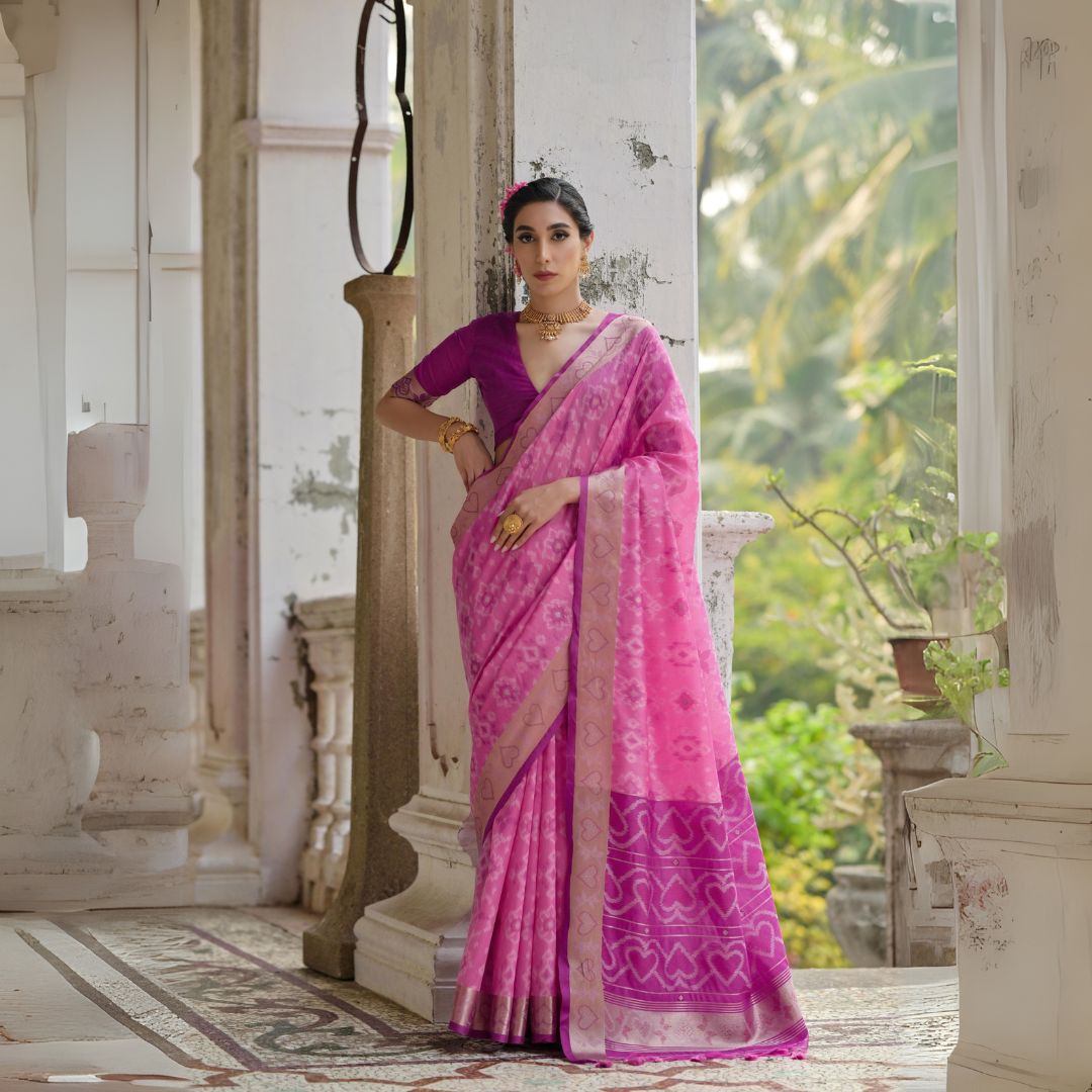Woman draped in light pink Pochampali Ikkat saree with intricate zari weaving, styled with traditional jewelry in a heritage setting