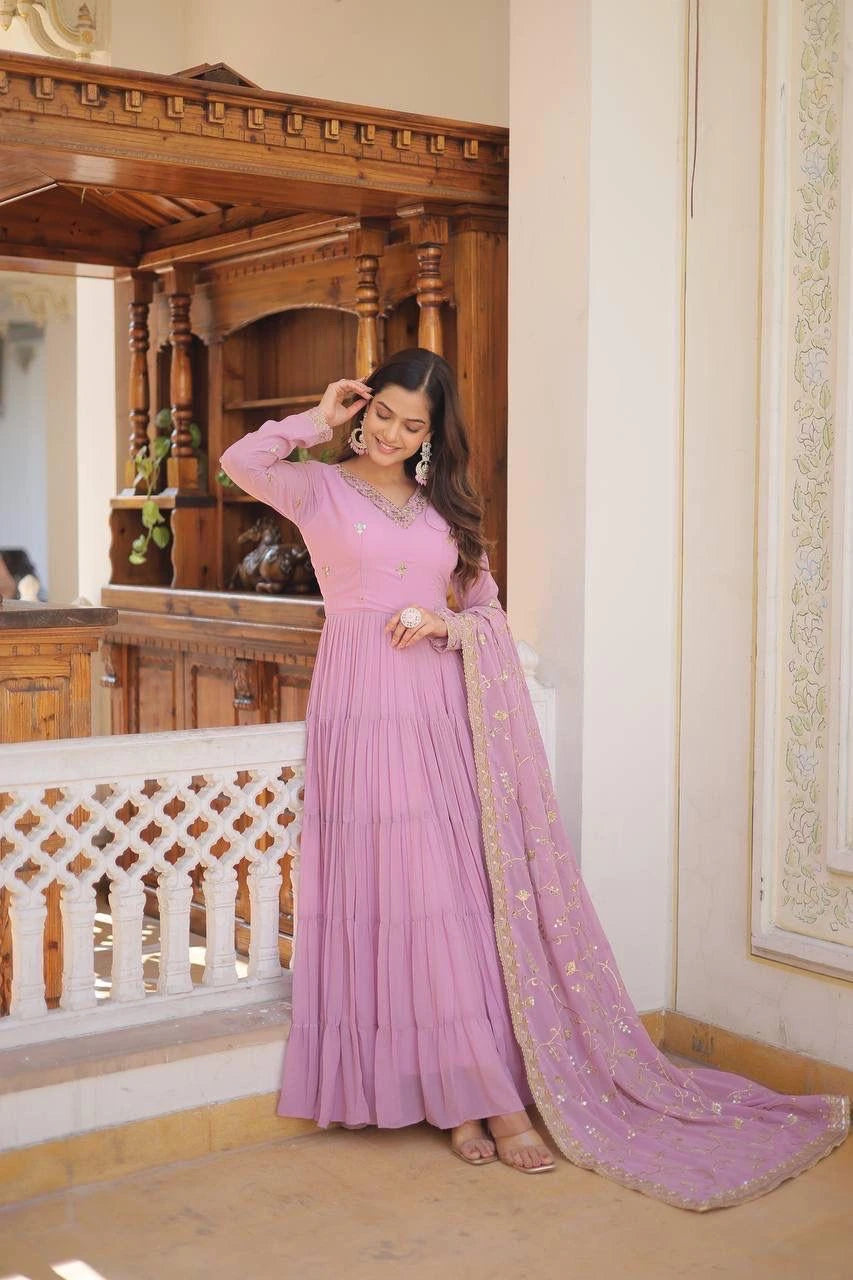 Woman in a pink saree standing indoors with wooden decor