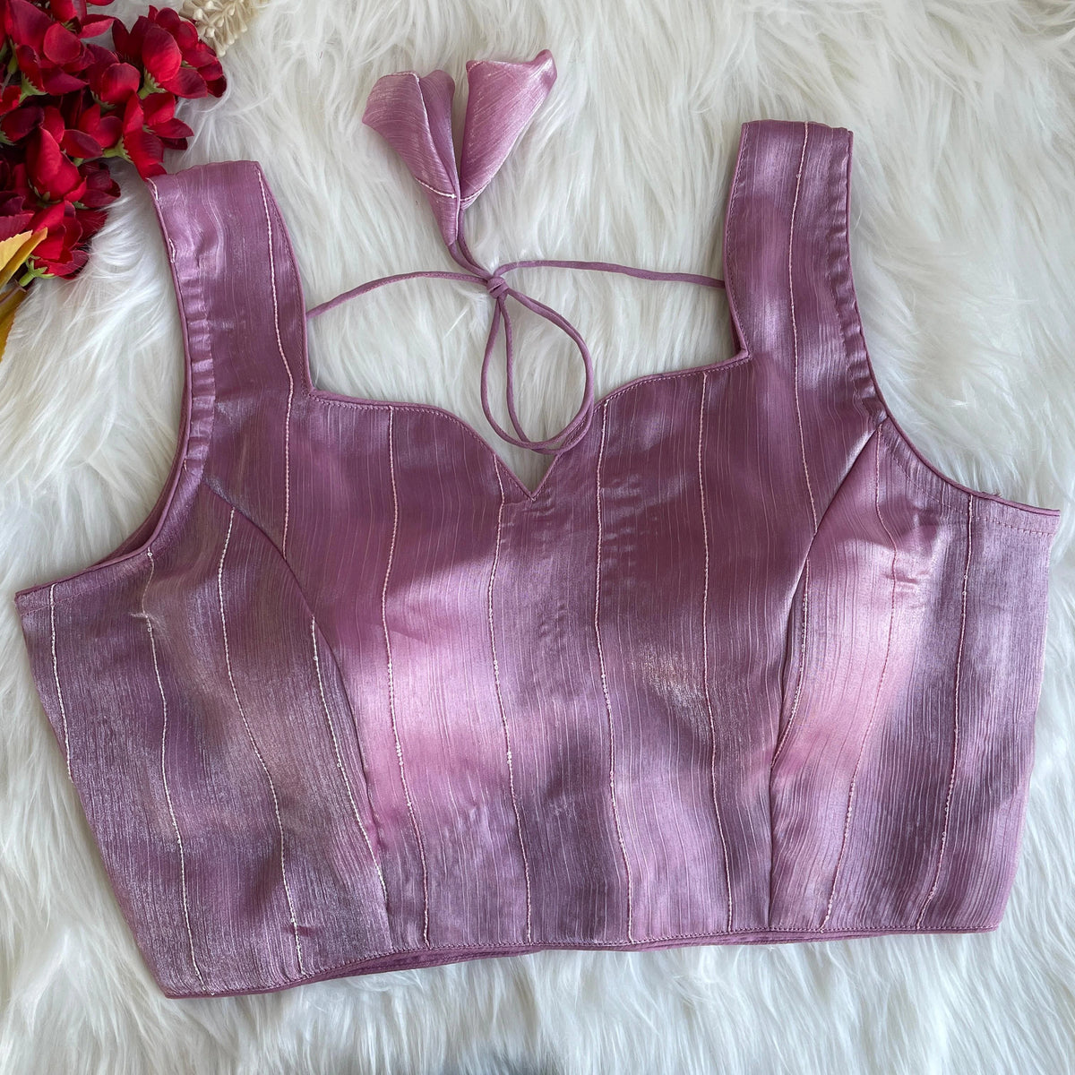 Purple crop top with matching hair accessory on a fluffy white surface with red flowers.