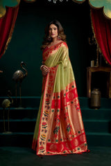 Woman wearing a traditional saree with red and green patterns in a dark setting.
