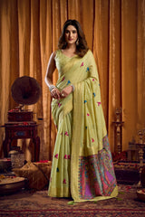 Woman in a light green saree with floral patterns in a vintage room.