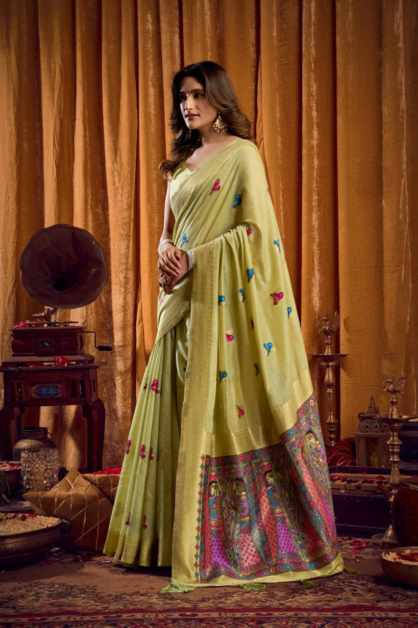 Woman in a light green saree with colorful patterns in a vintage room.