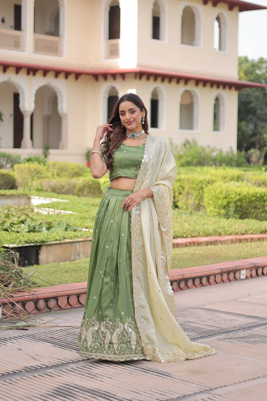 Woman in a green and white traditional outfit standing in front of a building with arches.