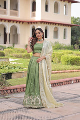 Woman in a green and white traditional outfit standing in front of a building with arches.