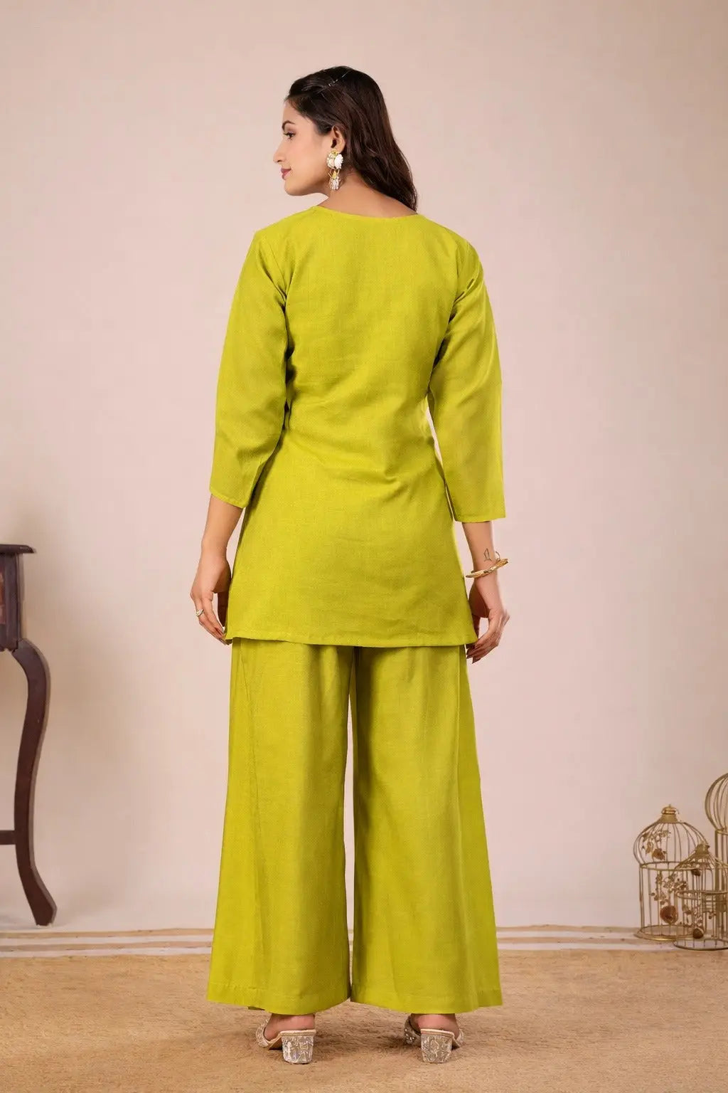 Woman wearing a green outfit with wide-leg pants against a beige background