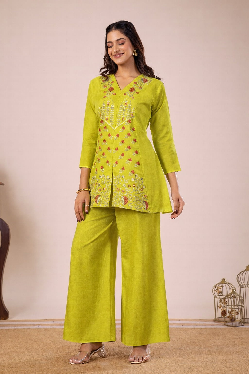 Woman wearing a bright green traditional outfit with a matching top and pants on a beige background