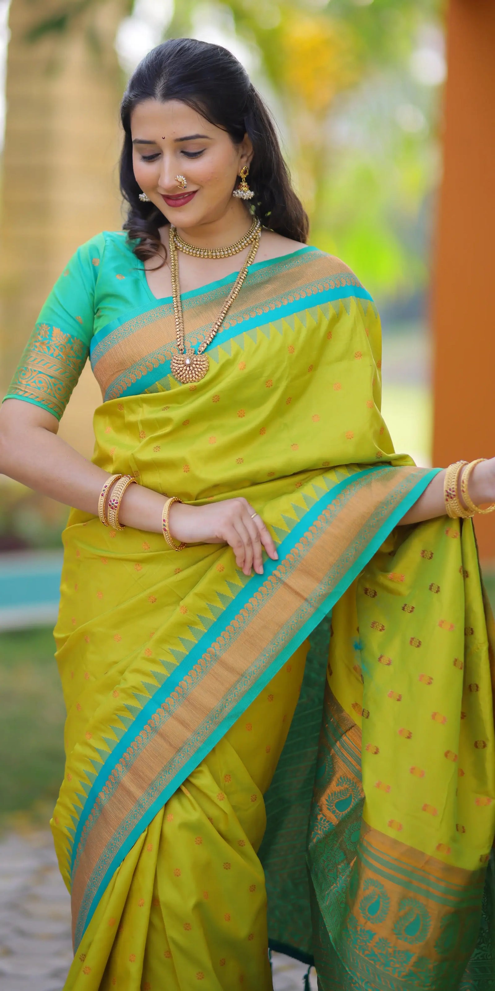 Woman wearing a bright yellow saree with green border outdoors