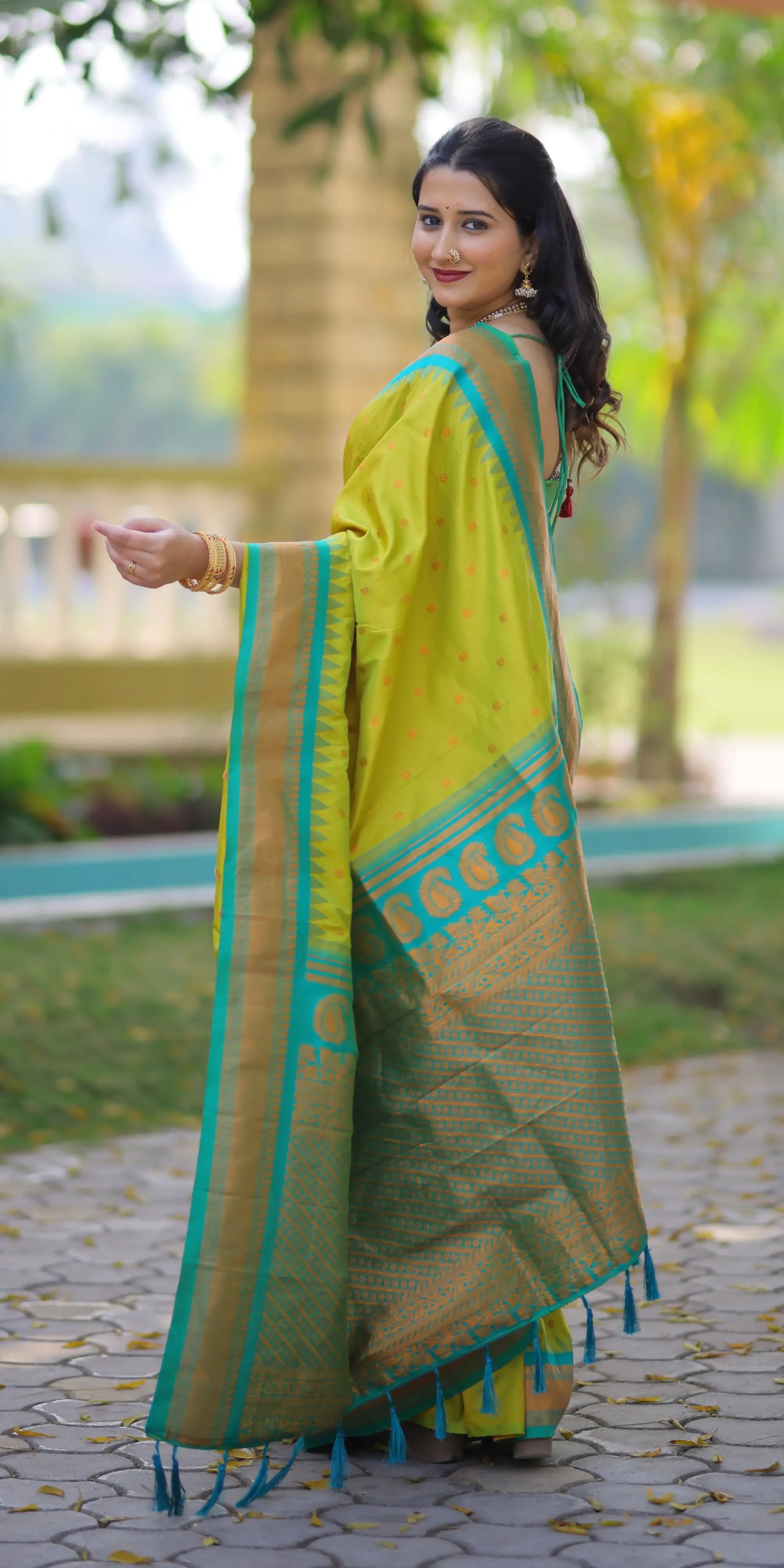 Woman wearing a green saree with blue border outdoors