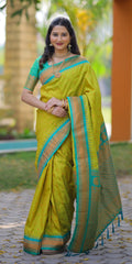Woman wearing a green saree with a blue border outdoors.