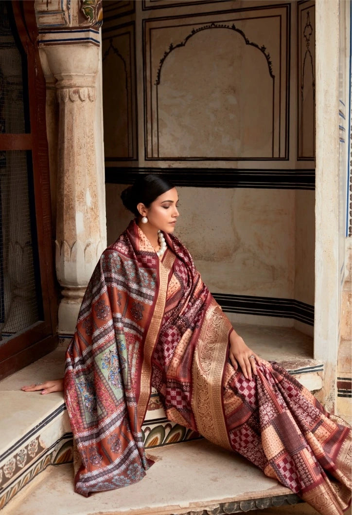Woman in a patterned saree sitting on a stone bench in an ornate room.