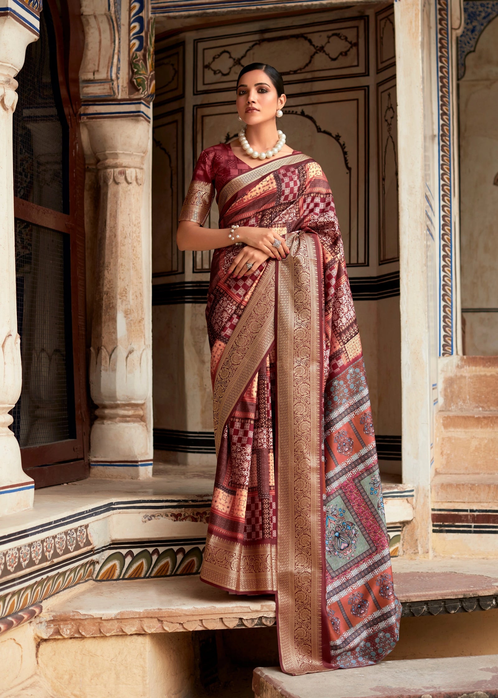 Woman in a traditional saree standing in an ornate architectural setting