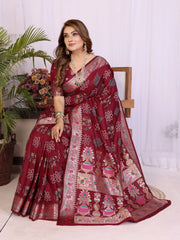 Woman wearing a maroon saree with floral patterns indoors.