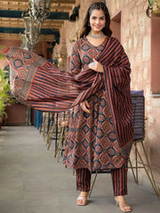 Woman in traditional patterned outfit with a scarf, standing indoors.
