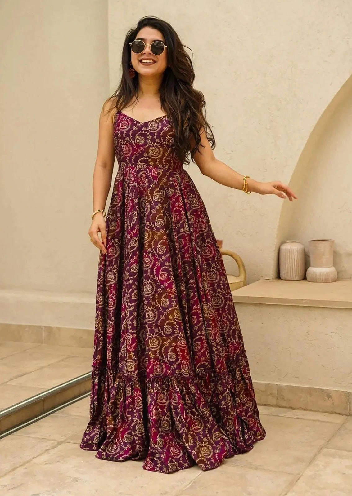 Woman in a patterned dress standing indoors with a neutral background