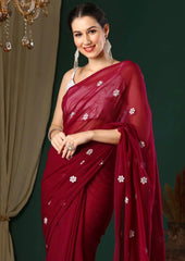 Woman wearing a red saree with white patterns against a dark background