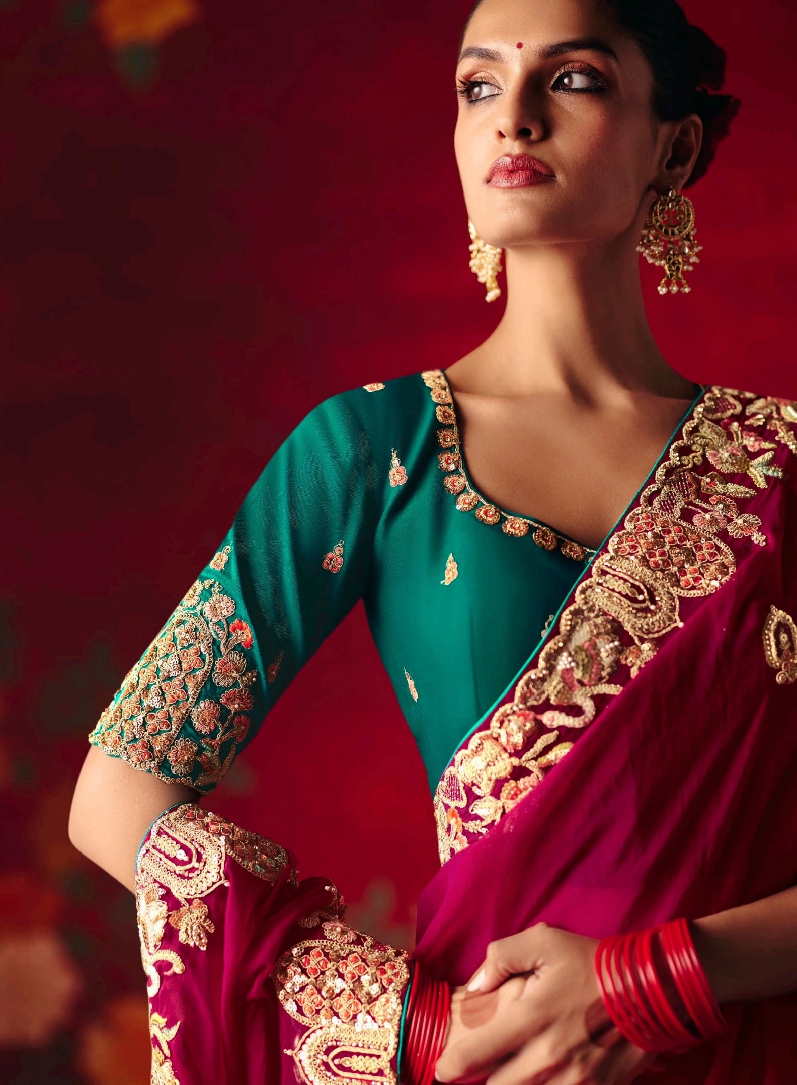 Woman wearing a traditional embroidered saree with a red background