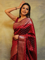 Woman wearing a red saree with gold patterns against a beige background