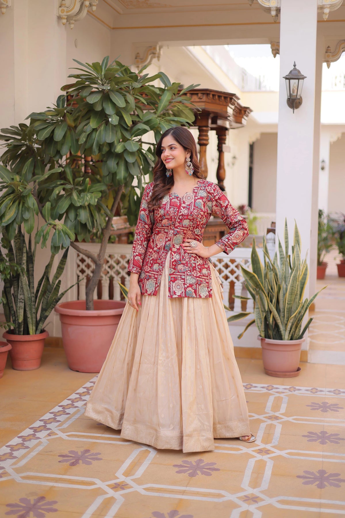 Woman in traditional outfit standing in a decorated outdoor setting with plants and architectural elements.
