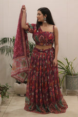 Woman in a floral outfit holding a matching dupatta with plants in the background