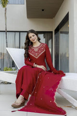 Woman in a red traditional outfit sitting on a white chair outdoors.