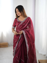 Woman wearing a maroon saree with silver border indoors
