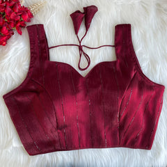 Red bikini top on a white fluffy surface with red flowers.