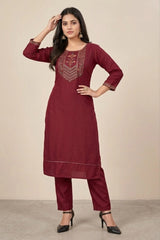 Woman wearing a maroon kurta with intricate embroidery on a beige background