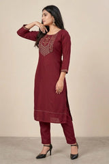 Woman wearing a maroon kurta with embroidery on a beige background