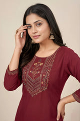 Woman wearing a maroon embroidered kurta against a beige background