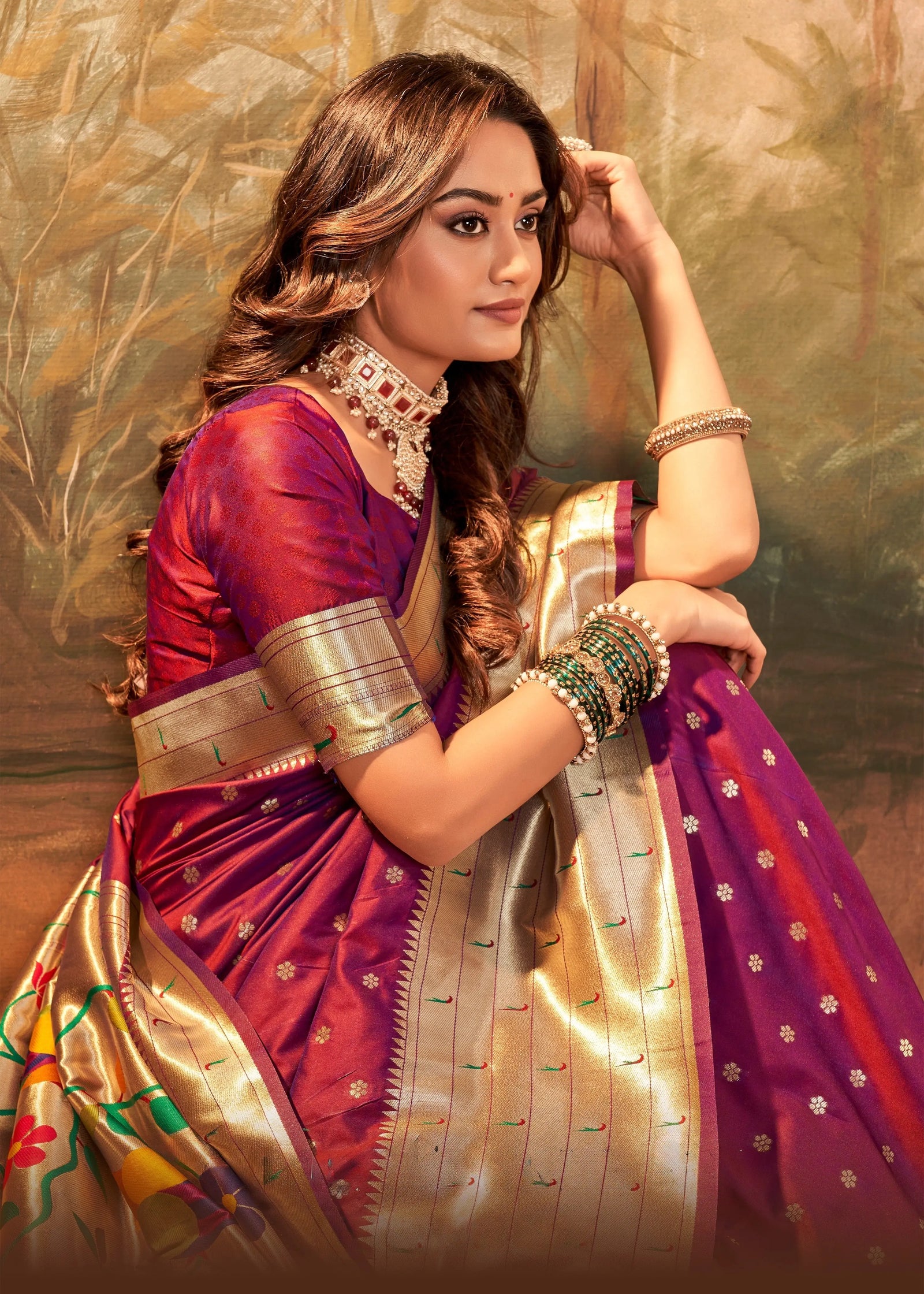 Woman in a traditional saree with a gold and purple color scheme against a textured background
