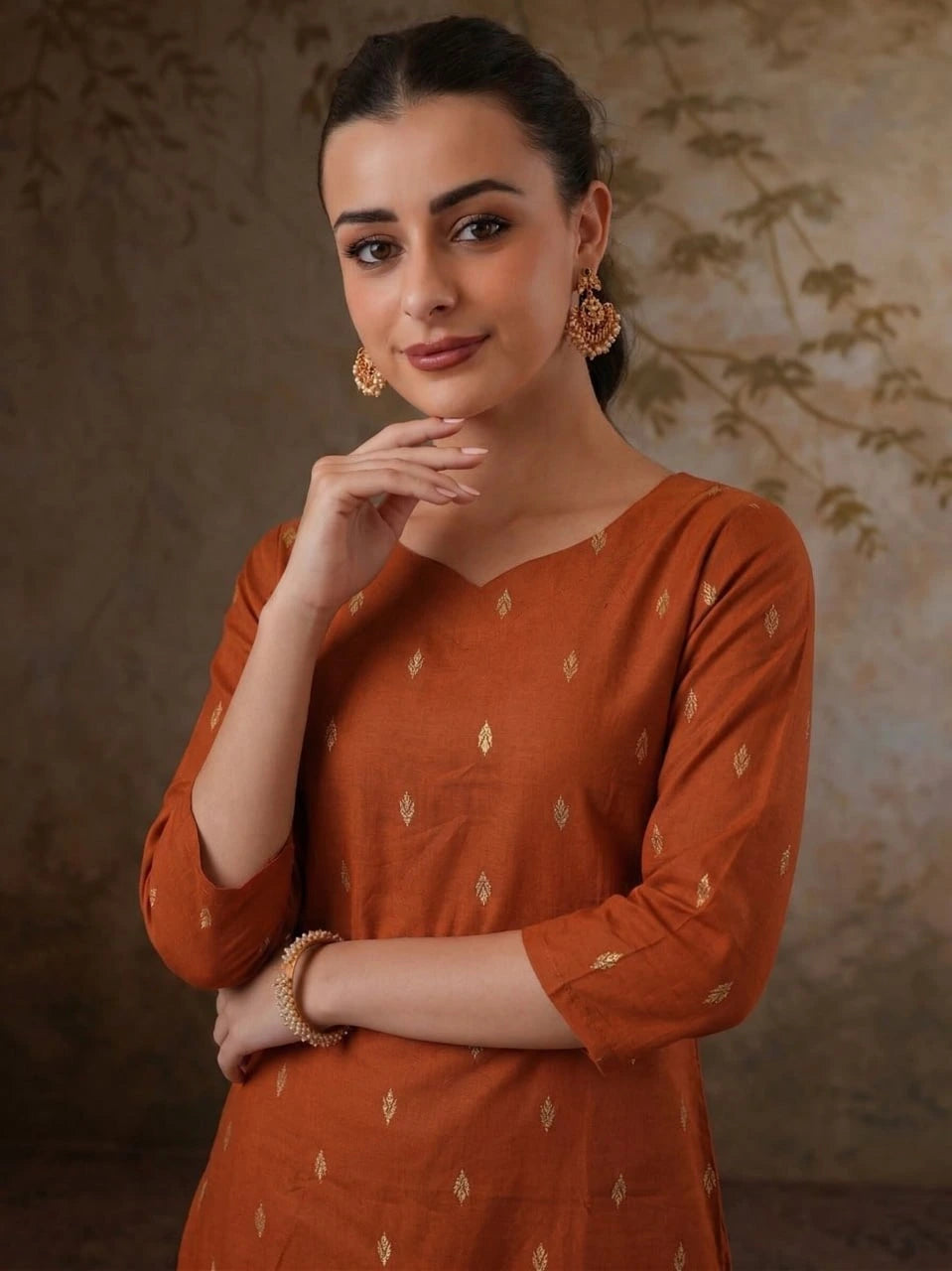 Woman wearing an orange traditional outfit with a subtle pattern against a textured brown background