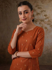 Woman wearing an orange traditional outfit with a subtle pattern against a textured brown background