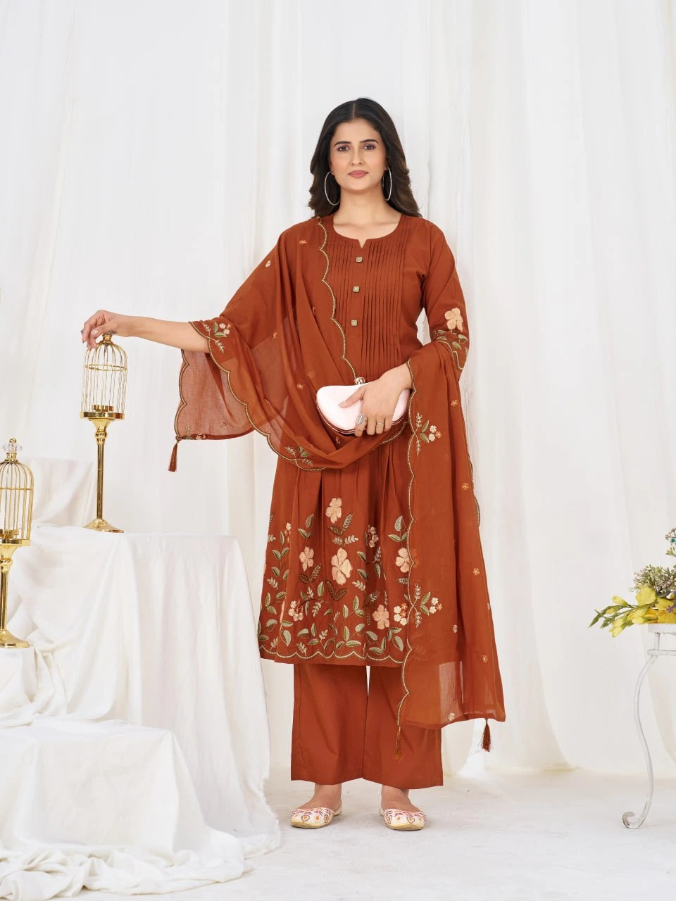 Woman wearing a brown embroidered outfit against a white background
