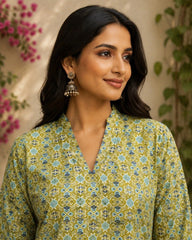 Woman wearing a green floral patterned top with earrings, against a floral background