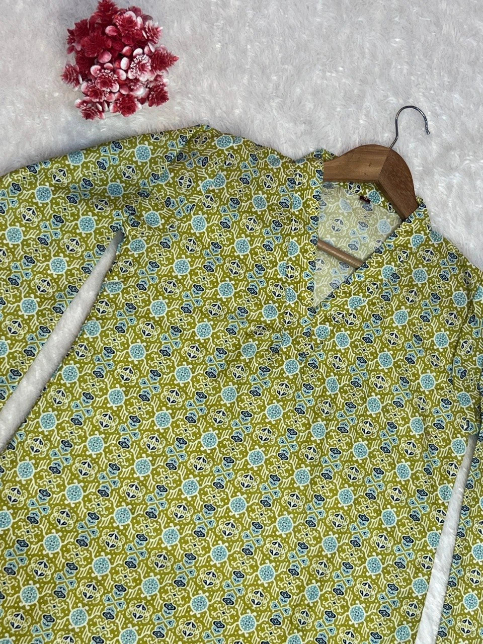 Floral patterned shirt on a hanger with a wooden hook against a textured white background