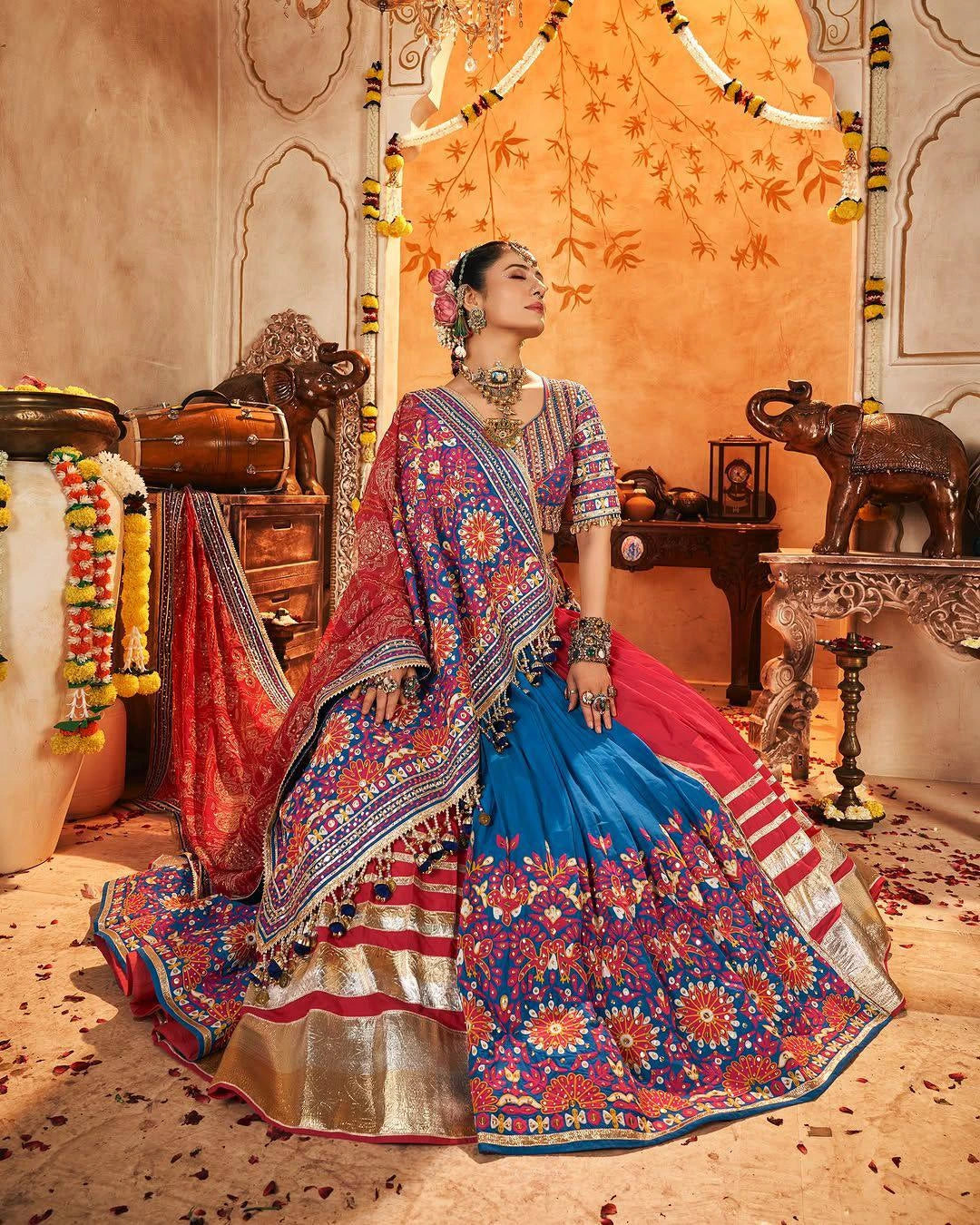 Woman in a colorful traditional outfit standing in an ornate room.
