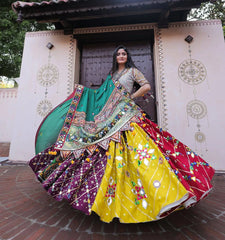 Woman in a colorful traditional outfit standing in front of a decorative building entrance.