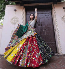 Woman in a colorful traditional outfit standing in front of a decorative door.