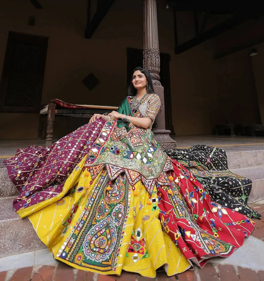 Woman in a colorful traditional outfit sitting on steps.