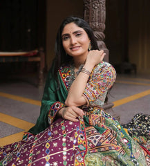 Woman in a colorful traditional outfit sitting on the floor.