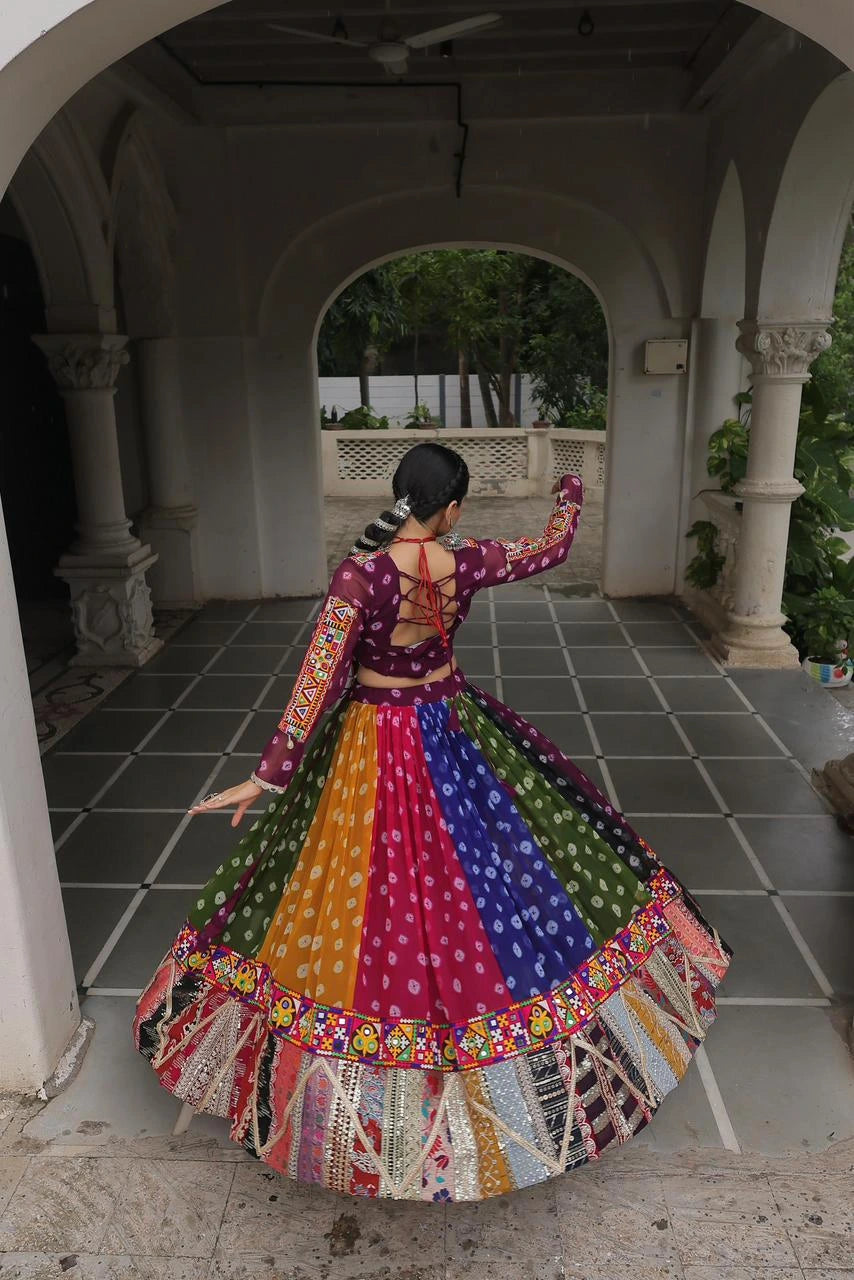 Person wearing a colorful traditional outfit in an outdoor setting with arches and greenery.
